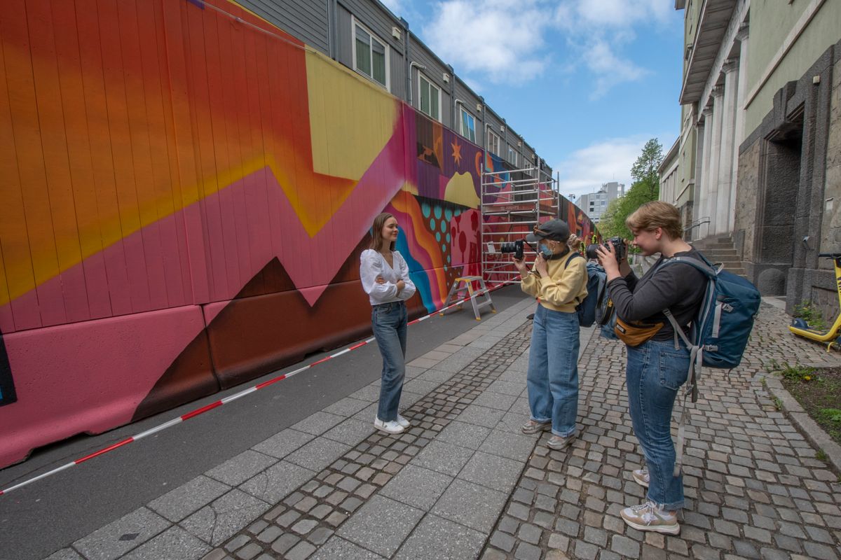Allerede før veggmaleriet er ferdig, har publikum fattet interesse for den fargerike veggen. Her blir Ulrikke Torgersen (fra venstre) fotografert av Christine Evjan og Erle Runde.