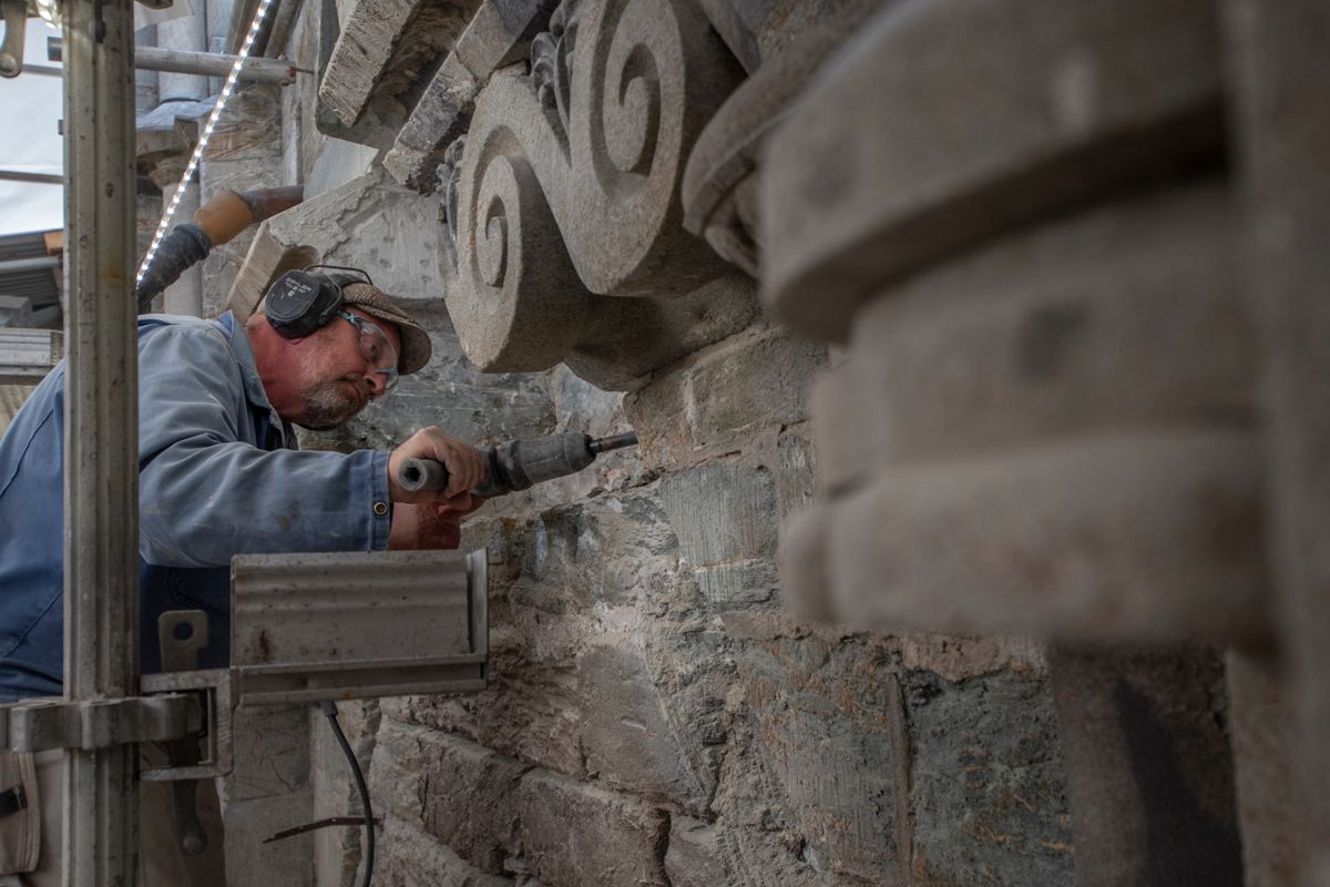 Murer og steinhugger Chris Pennock meisler løs over den rikt utsmykkede Kongeinngangen på Nidarosdomen. Til neste år skal de nyrestaurerte dørene åpne igjen.