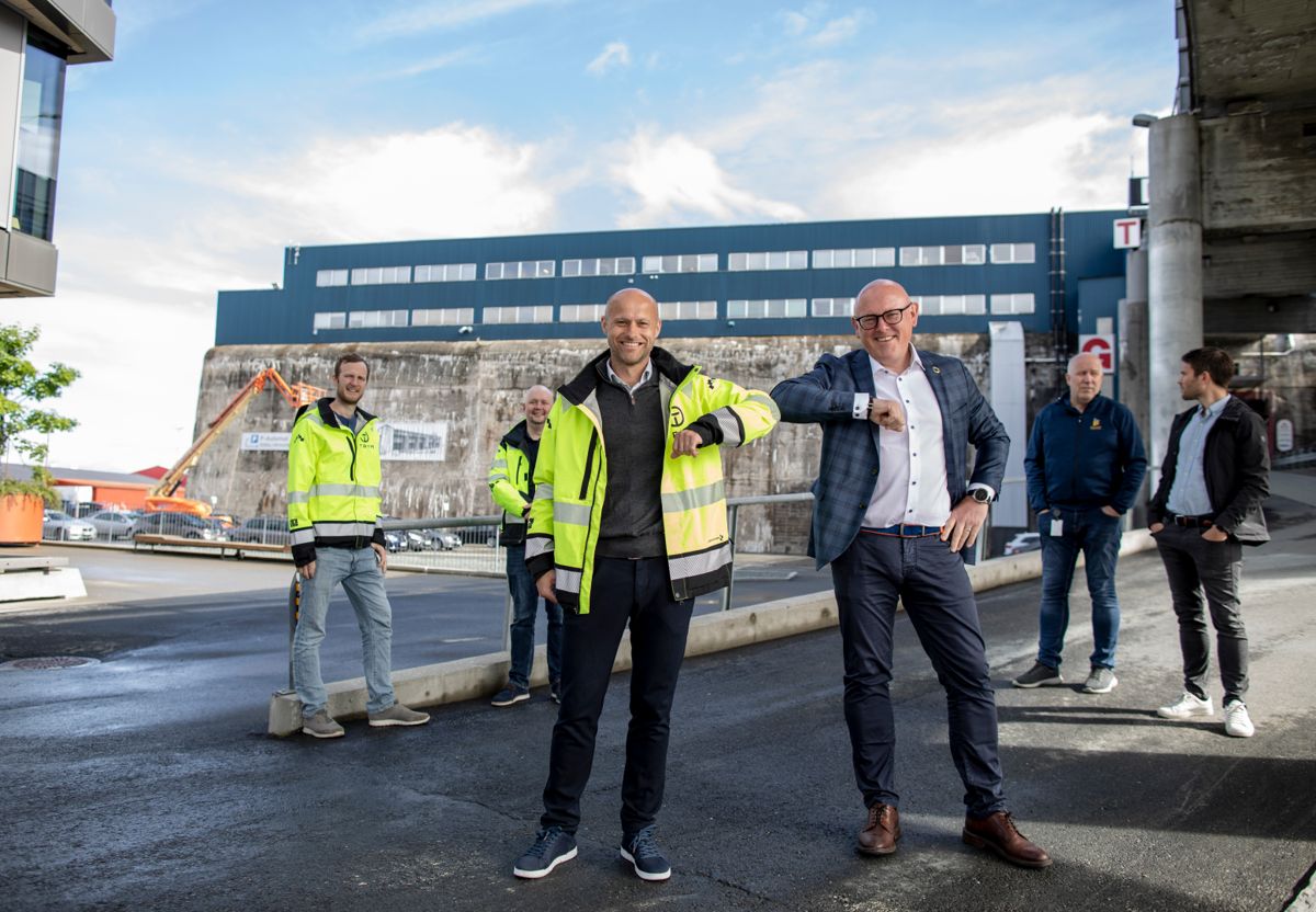 Daglig leder i Trym Bygg Robert Walnum Skjervstad og administrerende direktør i Dora Eiendom Geir Halmøy ved kontraktsignering. Fra venstre i bakgrunnen står kalkulatør/innkjøper i Trym Bygg Erlend Skarpnes, leder kalkulasjon/innkjøp i Trym Bygg Oddvar Henry Englund Stranden, prosjektleder i Byggherrerådgiveren Ulf Rian og utviklingssjef i Dora Eiendom Kristian Høgstad Lund. Foto: Anne Reisch.