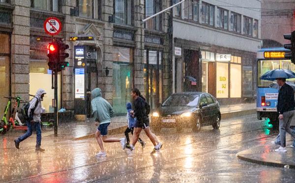Folk løper for å søke ly fra regnet i Oslo sentrum tirsdag. Uværet vil trolig fortsette utover helgen. Foto: Geir Olsen / NTB