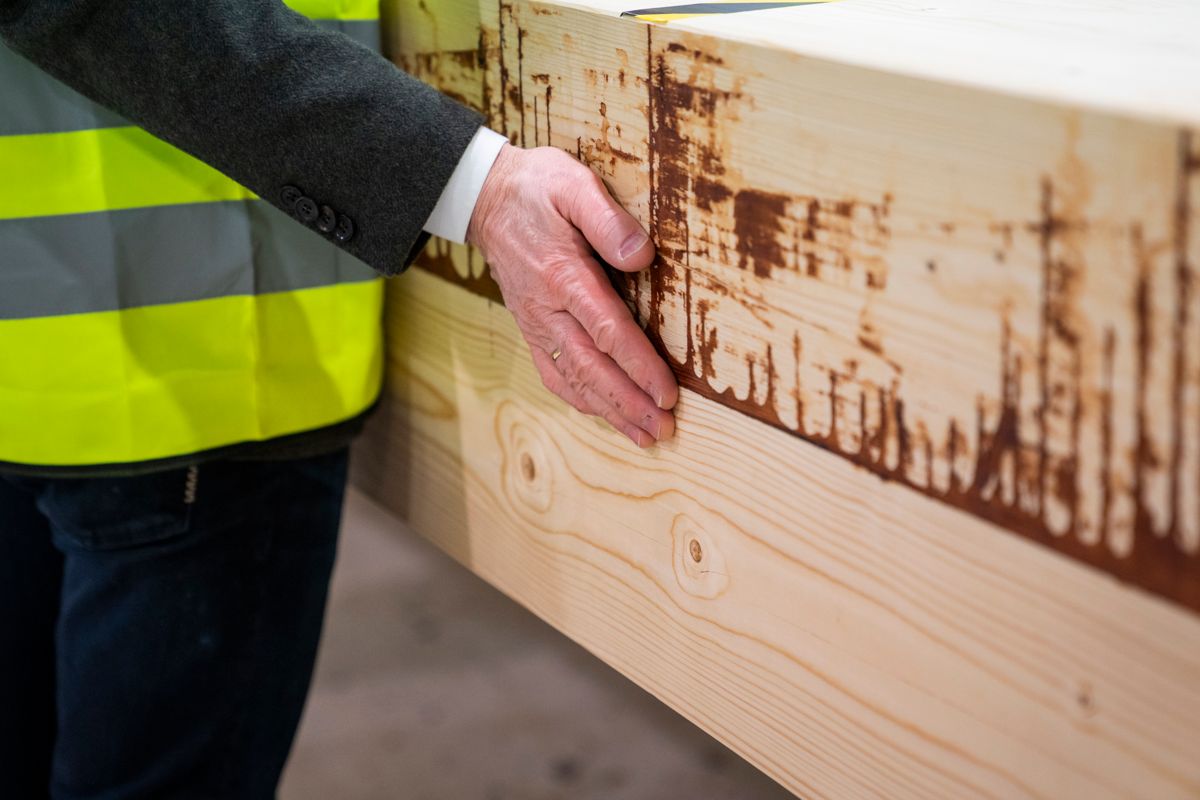 Statsminister Jonas Gahr Støre (Ap) kjenner med egne hender på strukturen i et av de store limtre-produktene til Moelven industrier. Foto: Håkon Mosvold Larsen / NTB