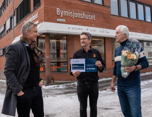 Konsernsjef Jon Ola Stokke i Garda Sikring (fra venstre) overrakte en pengesum på 80.000 kroner til seniorrådgiverne Jan Egil Hovland og Jon Dahl i Kirkens Bymisjon i Drammen. Foto: Garda Sikriing