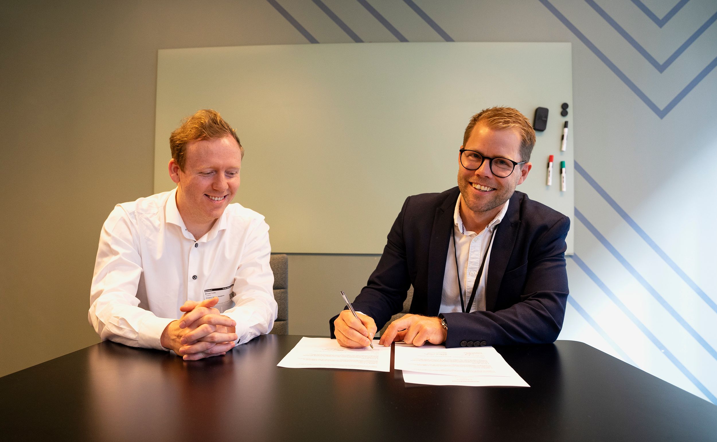 Michael Curtis i Loopfront (til venstre) og Benjamin Raugland i Fremtind signerer avtalen. Foto: Fremtind