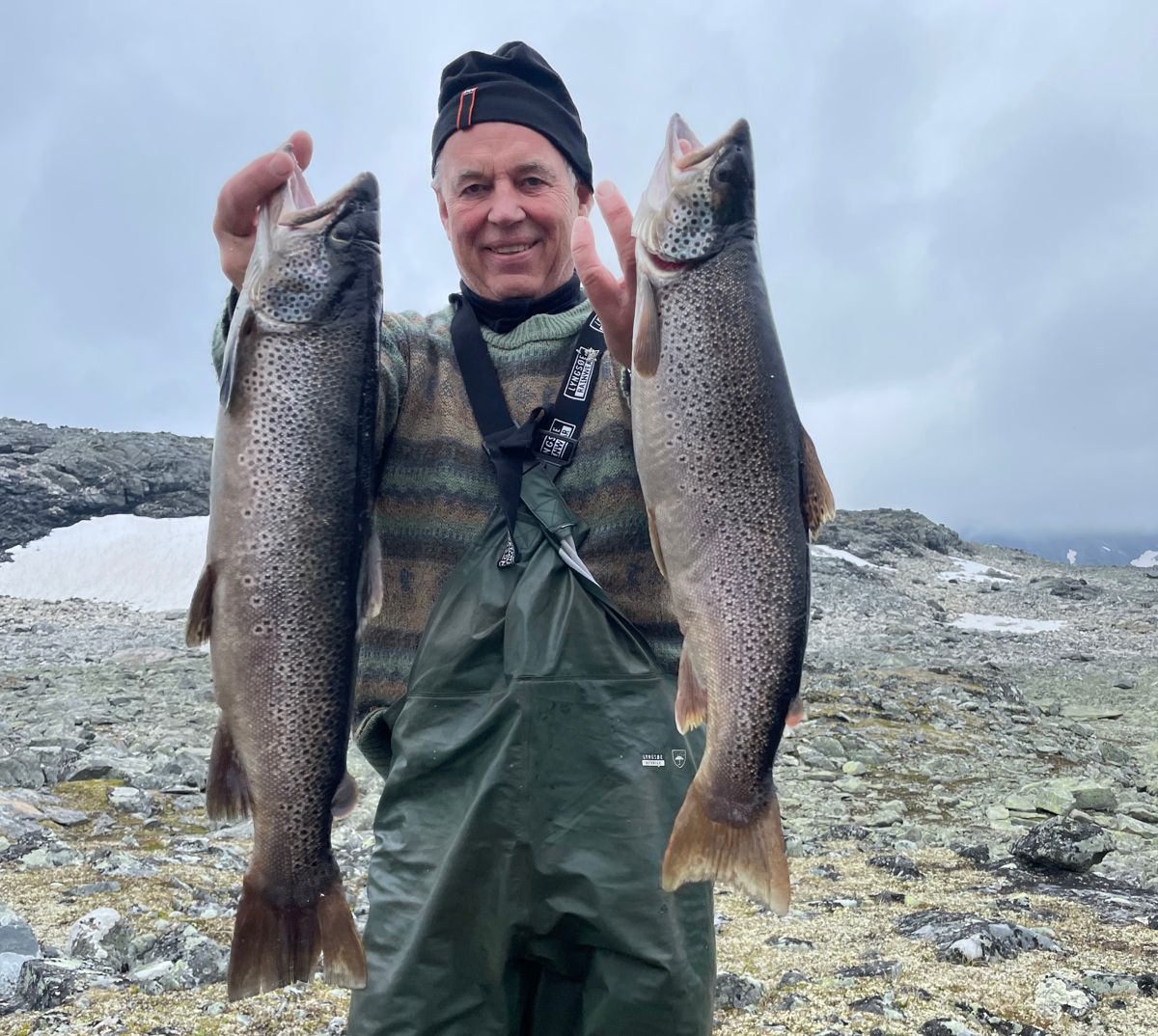 Anleggsveteranen Morten Wangen har høyfjellsfiske som hobby. Her med to store rugger fisket på et høytliggende vatn i Jotounheimen. Foto: Privat