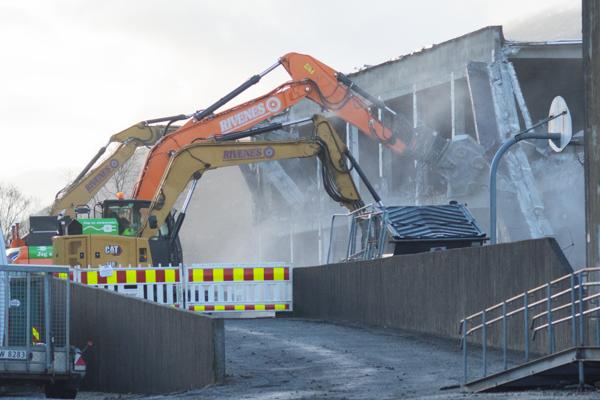 Tre elektriske gravemaskiner fra rive- og grunnentreprenøren Rivenes river et gammelt bygg for å gi plass til nye Garnes ungdomsskule. Foto: Ole Harald Dale