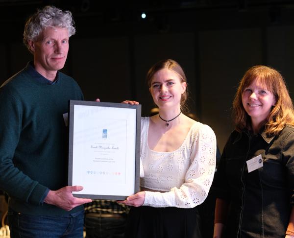 Tore Moen, leder for ekspertgruppe for akustikk og ekspertgruppemedlem Ivonne Verstappen deler ut prisen (diplom og 10.000 kroner) til Sarah Margrethe Løvald. Foto: RIF