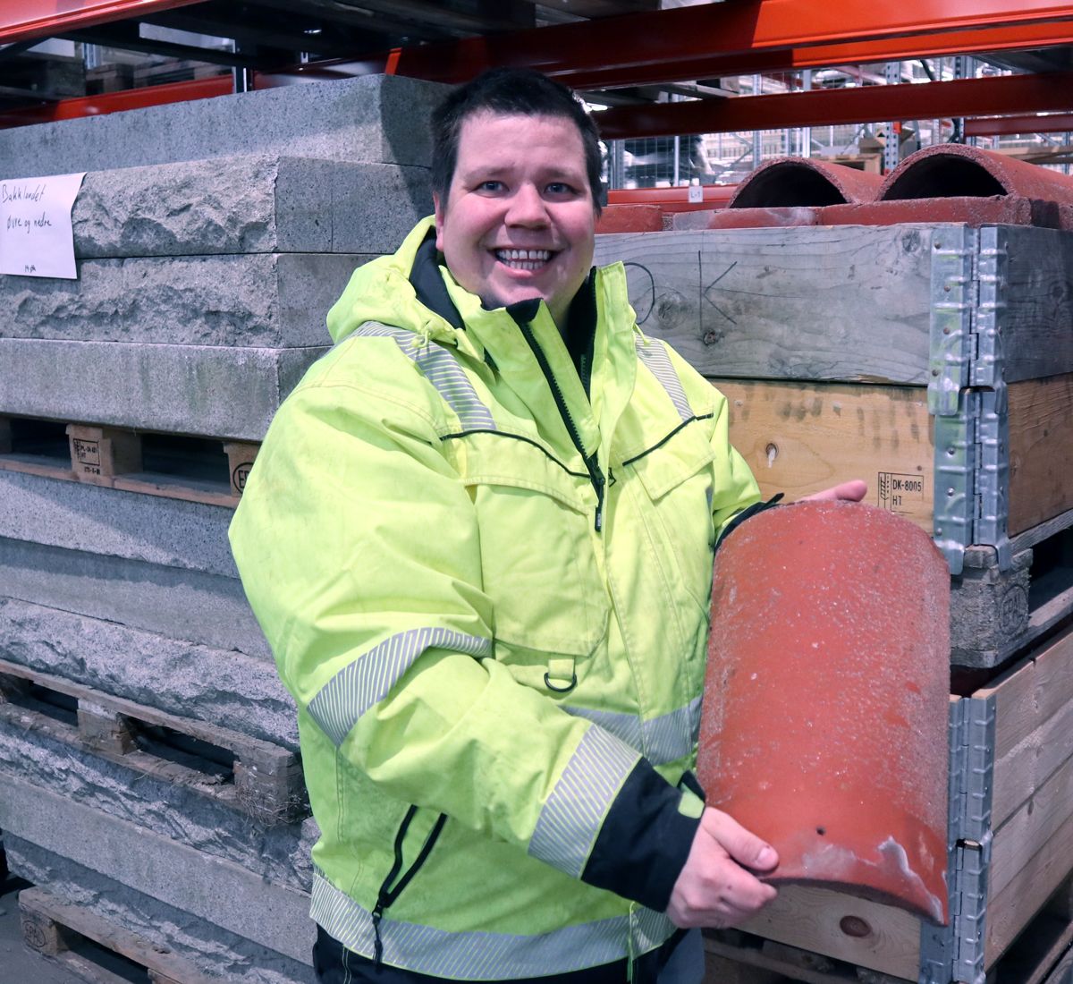 Taksteinen som gjenbrukskoordinator Petter Nerbye viser frem er 40 år gammel, men skal nå opp på taket på et nytt bygg ved Stavne aktivitetssenter. Foto: John Inge Vikan