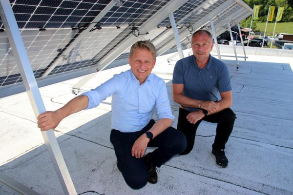 Konsernsjef i Isola Bjørnar Gulliksen og Isola Solar-direktør Anders Besvold Hansen setter seg på skyggesiden av solpanelene sine, men også der produseres det solenergi. Foto: Christian Aarhus