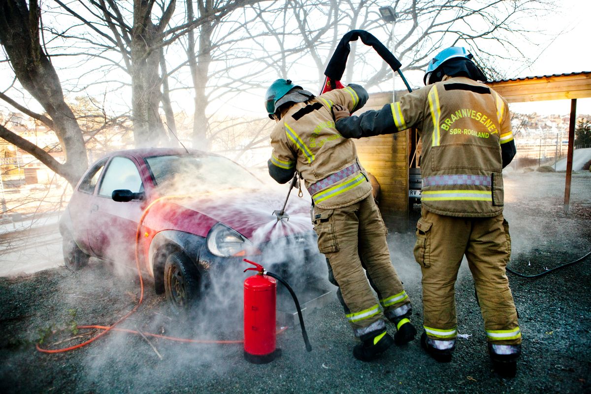 Her er to brannkonstabler fra Sør-Rogaland brannvesen i ferd med å slukke brann i en bil.