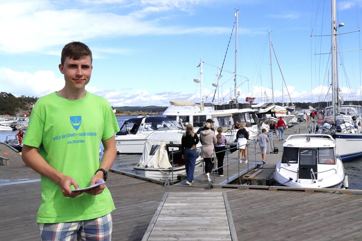 Herman Grytnes har sommerjobb som koronavert i Hvaler kommune. Han deler ut litt turistinformasjon og minner publikum på å holde avstand og vaske hender.