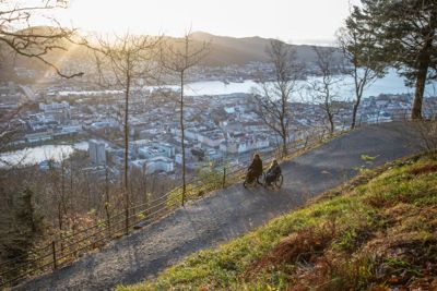 PÅ RULLETUR: Fløyen og Bergen ligger badet i sol når Annett Eidsvåg Garvik (til venstre) og Solvei Harila Skjold prøvekjører en av turveiene mot sentrum. De kommer seg ned, men underveis støter de på litt for mange utfordringer til at akkurat denne ruten kan anbefales som en av «Ti på hjul»-turene i Bergen. (Foto: Fredrik Naumann/Felix Features)