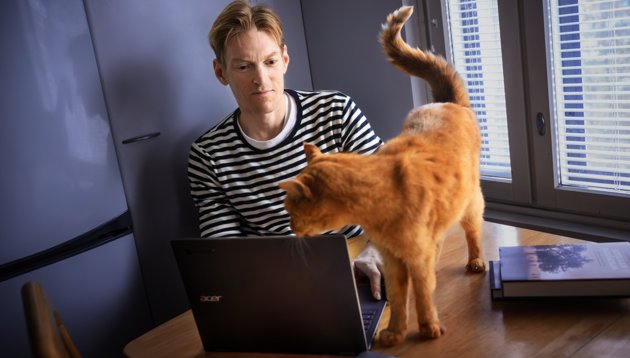 Fingrarna smattrar mot tangentbordet när Marcus Lindqvist skriver. Här håller katten Pulla ett öga på hans produktion.