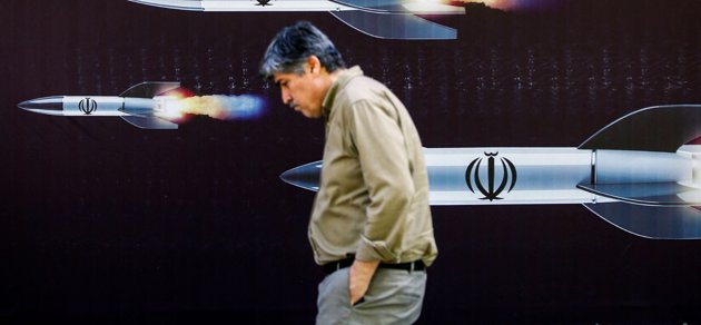 En man går förbi en poster som föreställer robotar i Teheran.