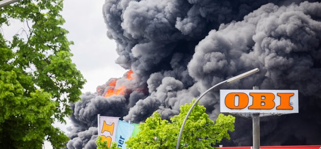 Stora svarta rökmoln bolmar från den brinnande fabriken.