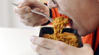 En man äter en färdig portion spagetti.