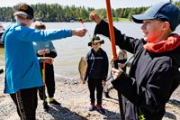 Elliot Vuorinen till höger, Isak Melleri i mitten och Tino Savolainen till vänster från Söderkulla skola beundrar en av de större fiskarna som drogs upp under fiskedagen.