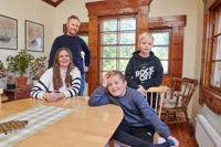 Familjen Hedman – föräldrarna Alex och Eleonore och sönerna Bill längst fram, 8 år, och Carl-Gustav, 10 år – har tagit plats i matsalen. Här liksom i övriga rum i huset är träsniderierna kring fönstren imponerande.