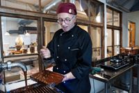 Gerald Coniel visar hur chokladkonfekt blir till. Fönstret bakom honom gör så att kunderna kan ta del av tillverkningsprocessen.