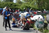 Flyktingar sitter på vägen under evakueringen av ett migrantläger i Grande-Synthe i norra Frankrike den 25 maj 2022.