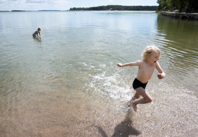 9-åriga Sini Selin räds inte den svala vattentemperaturen i juni utan simmar modigt, medan 6-åriga kusinen Jon nöjer sig med att springa omkring i grundare vatten.