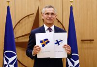 Natos generalsekreterare Jens Stoltenberg poserar med Finland och Sveriges underskrivna Natoansökningar den 18 maj.