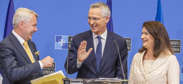Utrikesminister Pekka Haavisto erbjuder Natos generalsekreterare Jens Stoltenberg en fistbump. I sin vänstra hand bär han det anslutningsprotokoll som nu skickas till 30 medlemsländer för godkännande. Till höger Sveriges utrikesminister Ann Linde (socialdemokrat).