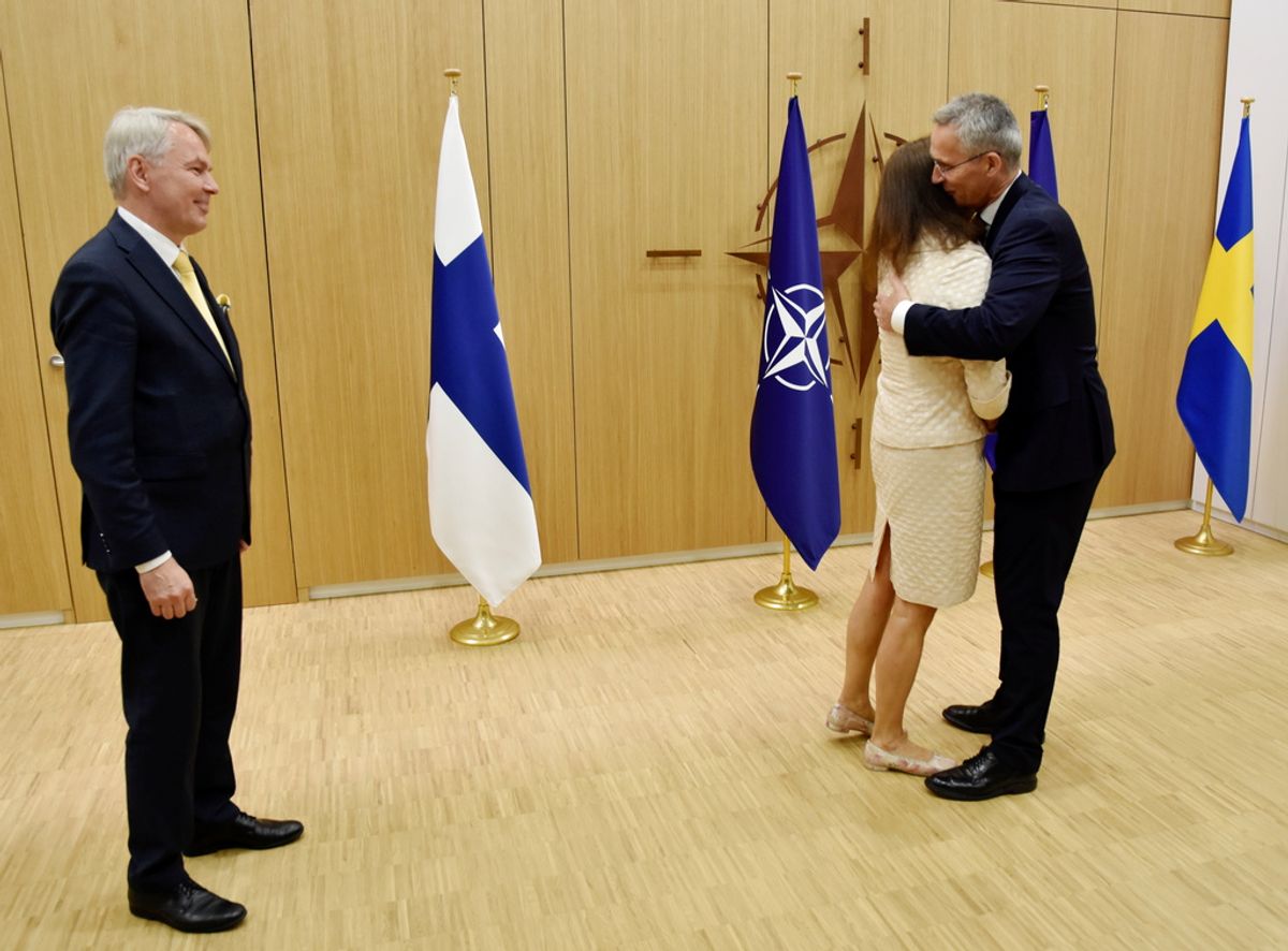 Finlands utrikesminister Pekka Haavisto ser på när Natochefen Jens Stoltenberg välkomnar Sveriges utrikesminister Ann Linde med en kram i Bryssel.