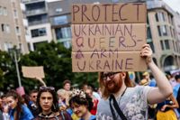 En Pridedeltagare håller upp en skylt där det står "Skydda Ukrainska queerpersoner. Tagen under en demonstration under Pridemånaden i Berlin. 