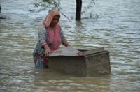 En kvinna har lagt sina tillhörigheter i en metallkista, i hopp om att rädda dem från vattnet i det översvämmade Jaffarabad i Baluchistan.