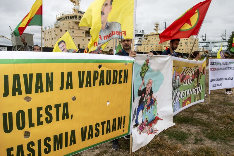 Kurdiska demonstranter protesterade utanför Utrikesministeriet i Helsingfors i augusti. Samtidigt träffades finska, svenska och turkiska representanter för trepartsförhandlingar i Vanda. Till höger PKK:s flagga.
