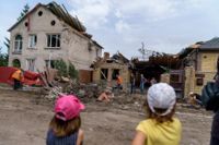 Två barn tittar på medan hjälparbetare städar upp efter ett bombnedslag i Kramatorsk i Donetsk. Bilden är tagen 12 augusti.