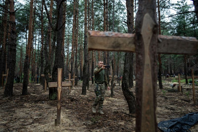 Gravplatsen utanför Izium med hundratalet gravar – många av dem märkta med bara ett nummer – dokumenteras av ukrainsk personal.
