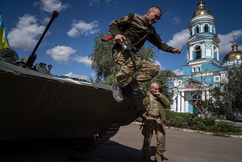 En ukrainsk soldat hoppar ned från ett fordon i staden Izium, som Ukraina nyligen återtog kontrollen över. Bilden togs i måndags.