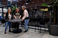 Här, vid den svarta glasväggen, ska Borgå biblioteks besökare få vara med och skapa ett konstverk. Malin Hollmén, Fanni Maliniemi och Sanni Saarinen är i full gång med att flytta bort borden.