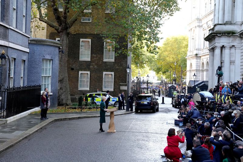 Liz Truss håller sitt sista anförande som brittisk premiärminister utanför 10 Downing Street, med sin familj i ryggen och ett stort pressuppbåd framför sig.