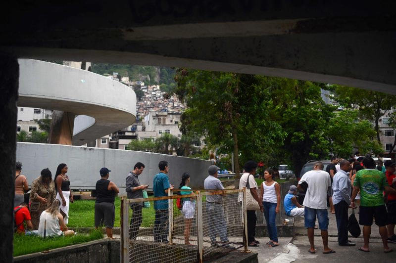 Så här köade folk för att rösta i Rio de Janeiro på söndagen, med Rocinha, stadens största favela (slumområde) i bakgrunden. Ekonomin är en stor utmaning i landet.