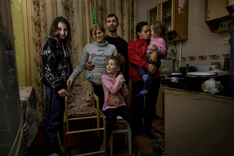 Rusalina Bedran, Nadija Ignatenko, Juryj Ignatenko, Karolina Bedran och grannfamiljen Margarita Belokrylaja med dottern Veronika i famnen hjälper varandra att klara vardagen i Cherson utan el, värme och rinnande vatten. En iPhone är placerad ovanpå det strömlösa kylskåpet och lyser upp köket.