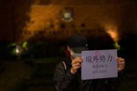 En demonstrant vid ett universitet i Hongkong håller upp ett budskap som bland annat kritiserar maktfullkomlighet hos regeringen. Bilden togs på tisdagskvällen.