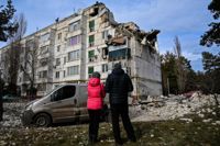 Lokala tittar på ett bostadshus som skadats av en missilattack i byn Kluhyno-Bashkyrivka, Kharkiv-regionen.