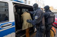 Poliser leder en av de gripna, en tysk adelsman, in i en piketbuss i Frankfurt. Omkring 3|000 poliser deltog i tillslaget mot den högerextrema gruppen i Tyskland.