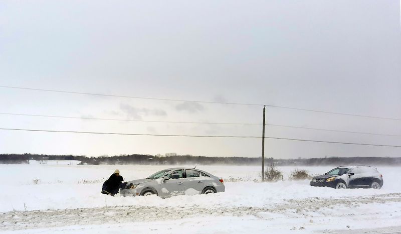 Samarbete mot snön. Några personer försöker knuffa loss en bil som kört fast utanför Montréal, sydöstra Kanada.