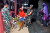 Indonesiska soldater hjälper kvinnor och barn upp på en militärbil efter att de har varit fast till sjöss i flera veckor.