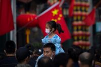 En flicka i munskydd på sin pappas axlar på en shoppinggata i Peking i oktober 2022.