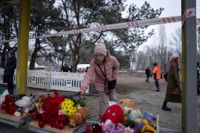 En kvinna lämnar en blombukett vid en busshållplats för att hedra de som dödades i den ryska attacken mot Dnipro.