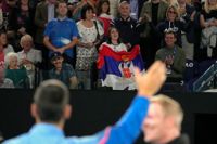 Novak Djokovic vinkar till sin familj – pappa Srdjan är mannen i mitten, bakom den serbiska flaggan – efter segern i Australian Open-kvartsfinalen mot ryssen Andrej Rubljov.