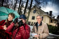 Clara Palmgren, Henrik Bremer och Christoffer Lindqvist är tre av de aktiva pensionärerna bakom svenska kulturföreningens nya fotoutställning om hus och villor i Grankulla. I bakgrunden står ett av objekten i samlingen, ett rappat timmerhus från 1940-talet, till vissa delar byggt av återvunnet material från hus som revs.
