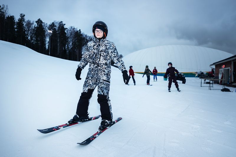 Winston Honkavuo och de övriga barnen får lära sig grunderna i alpin skidåkning under den 10 veckor långa hobbyklubben. – Efter att de gått i klubben borde skoleleverna klara av att åka i de flesta skidbackar i Finland, säger skidskolans chef Crista Järvikare.