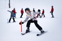 10-åriga Lilly Wilén övar på mjuka svängar i slalomklubben som Grankulla stad ordnar i samarbete med skidföreningen Grankulla Alpin i Granibacken. I bakgrunden syns skidlärarna och en del av slalomgruppen.