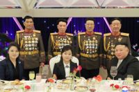 Vid bordet, från vänster: Diktatorsfrun Ri Sol Ju, dottern Kim Ju-Ae och diktatorn själv, Kim Jong-Un. Bakom dem står flera höga ledare inom militären. Bilden har distribuerats av Nordkorea via landets propagandamedier.