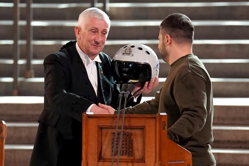 Det brittiska underhusets talman Sir Lindsay Hoyle tar emot en pilothjälm av Volodymyr Zelenskyj.